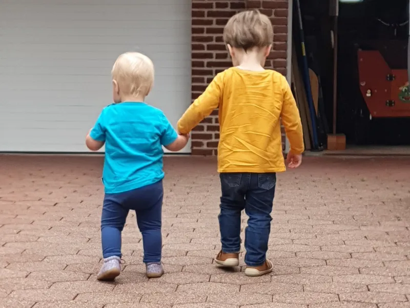 Zwei Kinder gehen Hand in Hand spazieren – gemeinsame Ausflüge fördern Vertrauen und soziale Entwicklung