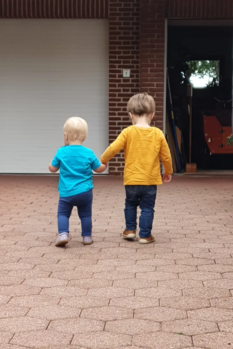 Zwei Kinder gehen Hand in Hand spazieren – gemeinsame Ausflüge fördern Vertrauen und soziale Entwicklung