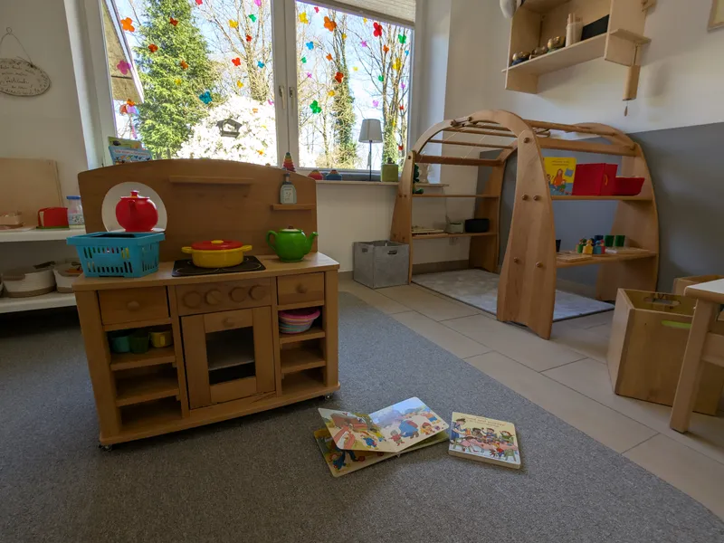 Kinderfreundlicher Spielbereich mit Holzküche, Lernmaterialien und natürlichen Spielzeugen für entwicklungsförderndes Spielen