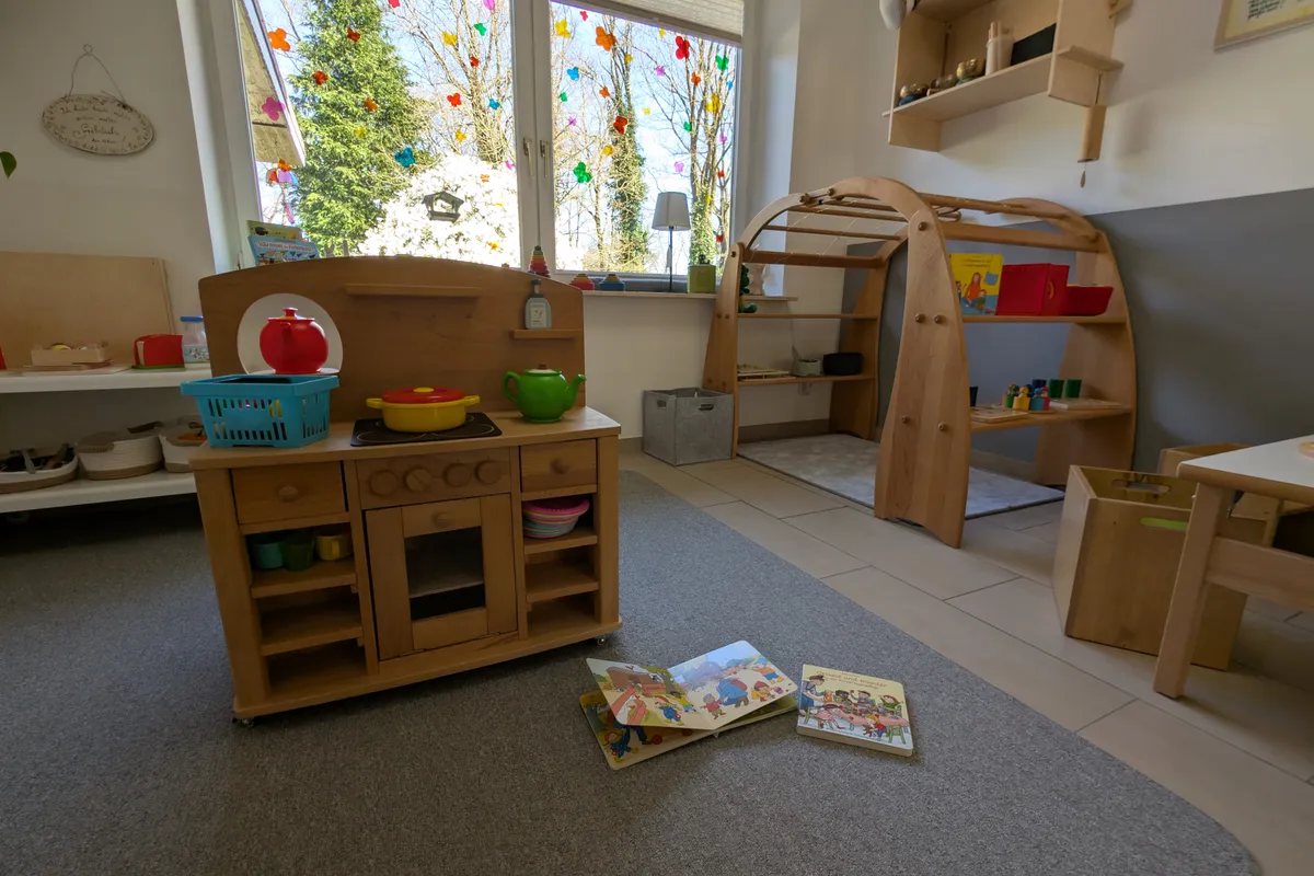 Kinderfreundlicher Spielbereich mit Holzküche, Lernmaterialien und natürlichen Spielzeugen für entwicklungsförderndes Spielen