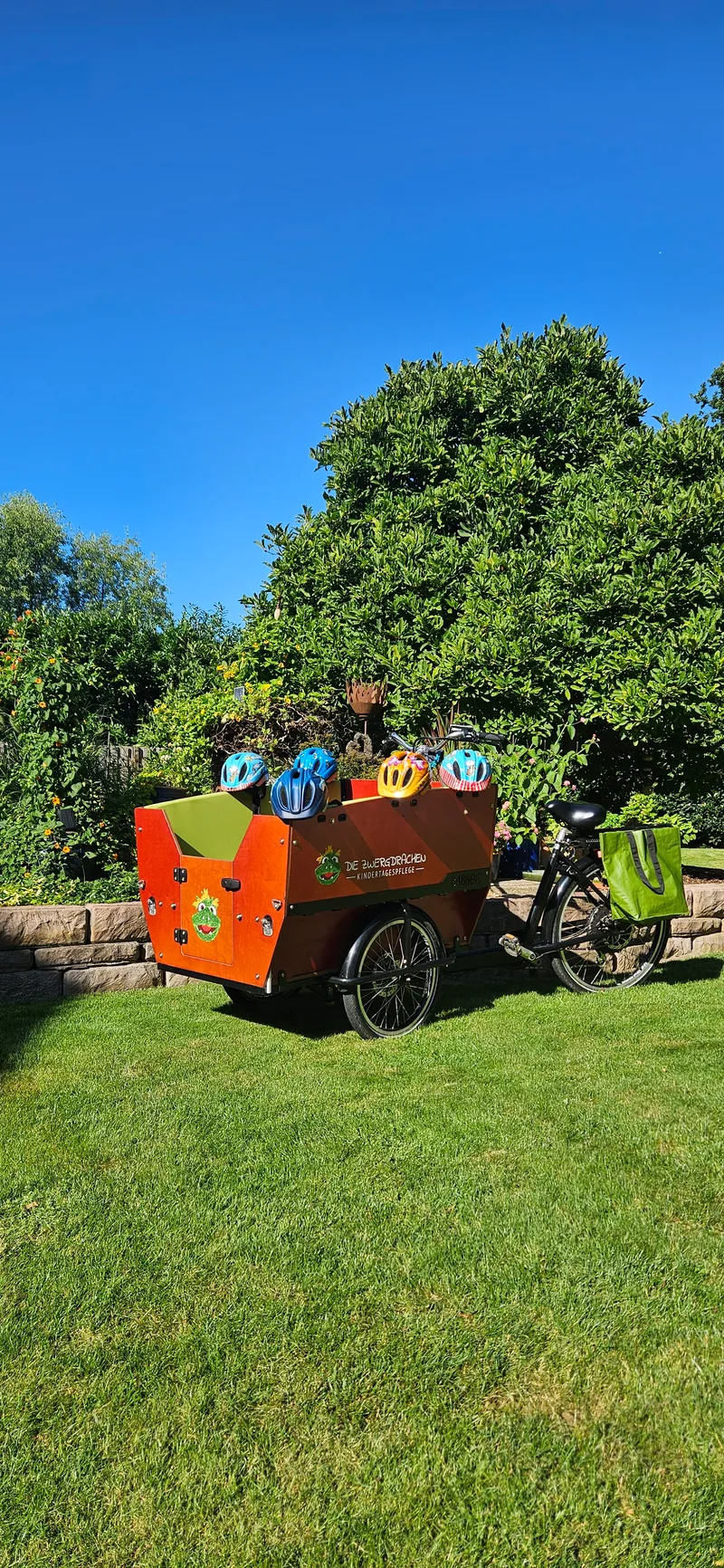 Lastenfahrrad im Garten bereit für den nächsten Ausflug – sicheres Transportfahrrad mit Helmen