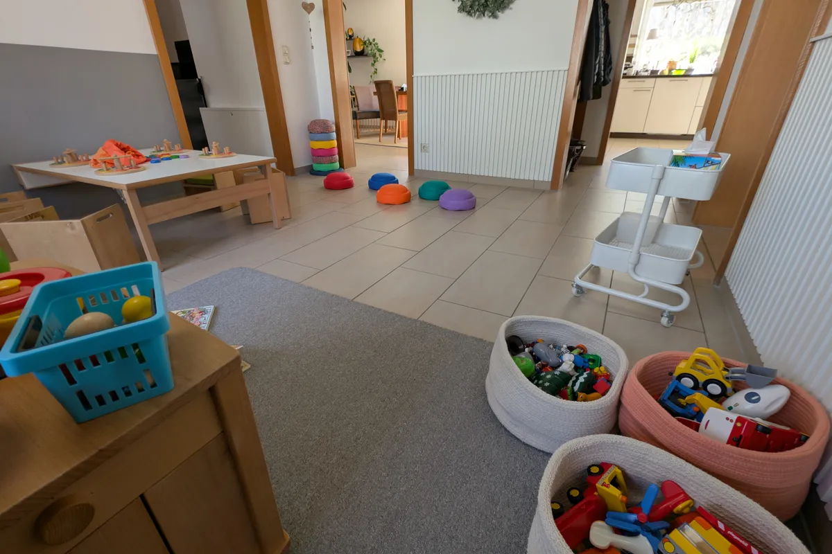 Organisierter Spielbereich mit zugänglichen Aufbewahrungskörben, Bewegungsparcours und kindgerechten Möbeln