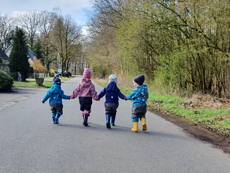 Vier Kinder halten Hände bei einem Spaziergang in die Natur – gemeinsame Ausflüge fördern soziale Bindung