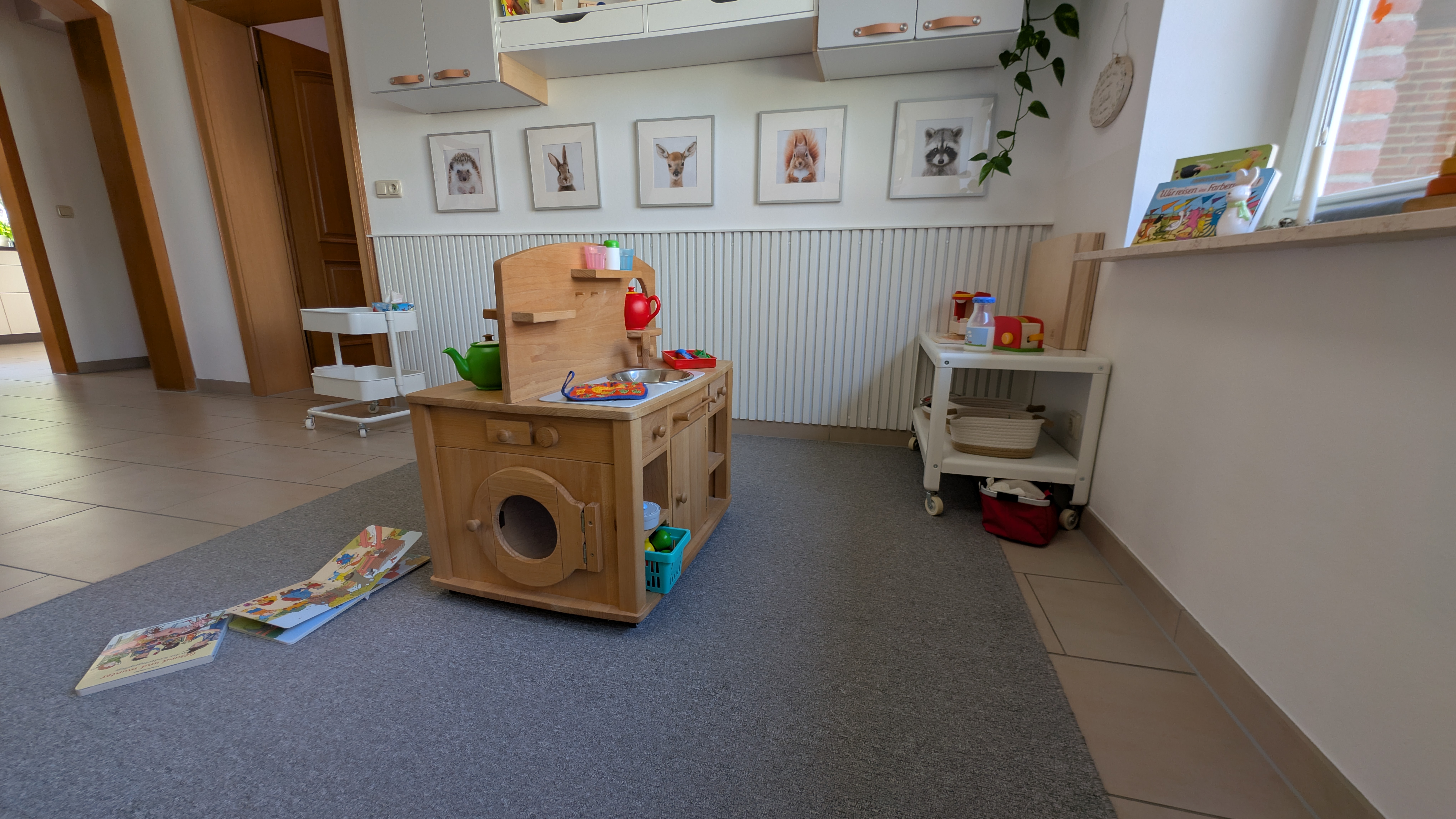 Kinderfreundlicher Spielbereich mit Holzküche, Lernmaterialien und natürlichen Spielzeugen für entwicklungsförderndes Spielen